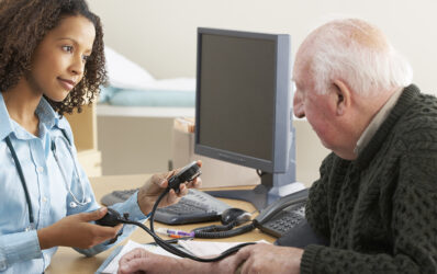 Healthcare professional taking an elderly man's blood pressure