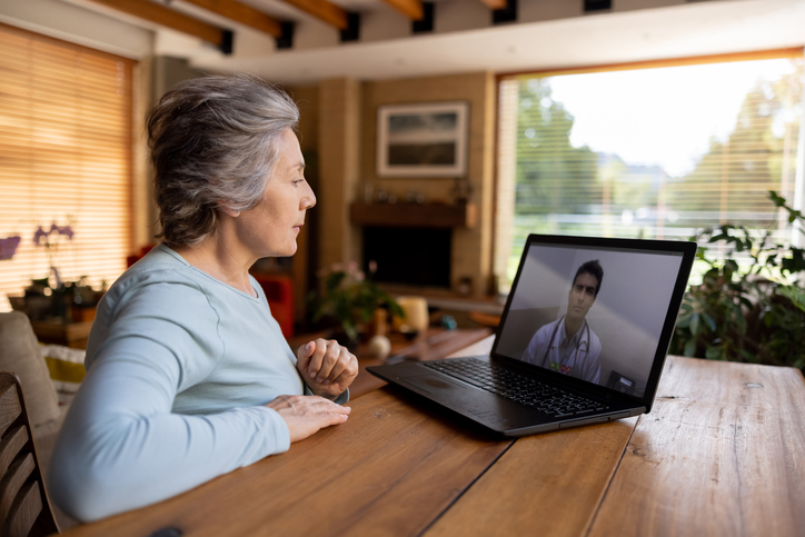 Older female receive telehealth care virtually on laptop.