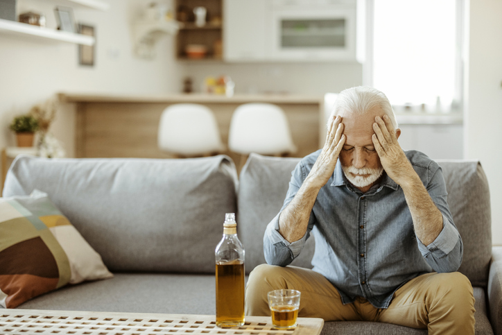 Substance Use Disorder. Senior man drinking alcohol at home alone, thinking about substance use and drinking problems with glass of whiskey.