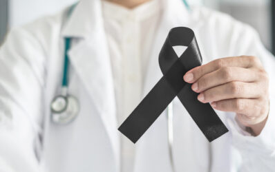 Black ribbon awareness in doctor's hand for Melanoma and skin cancer.