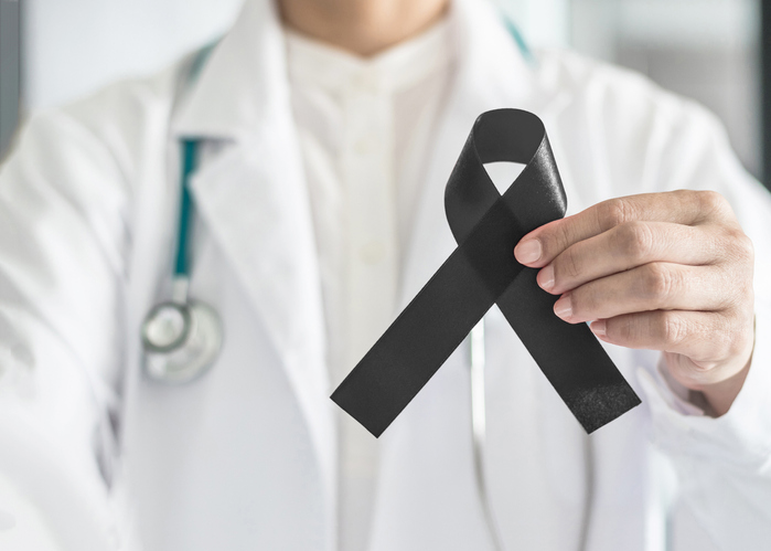 Black ribbon awareness in doctor's hand for Melanoma and skin cancer.